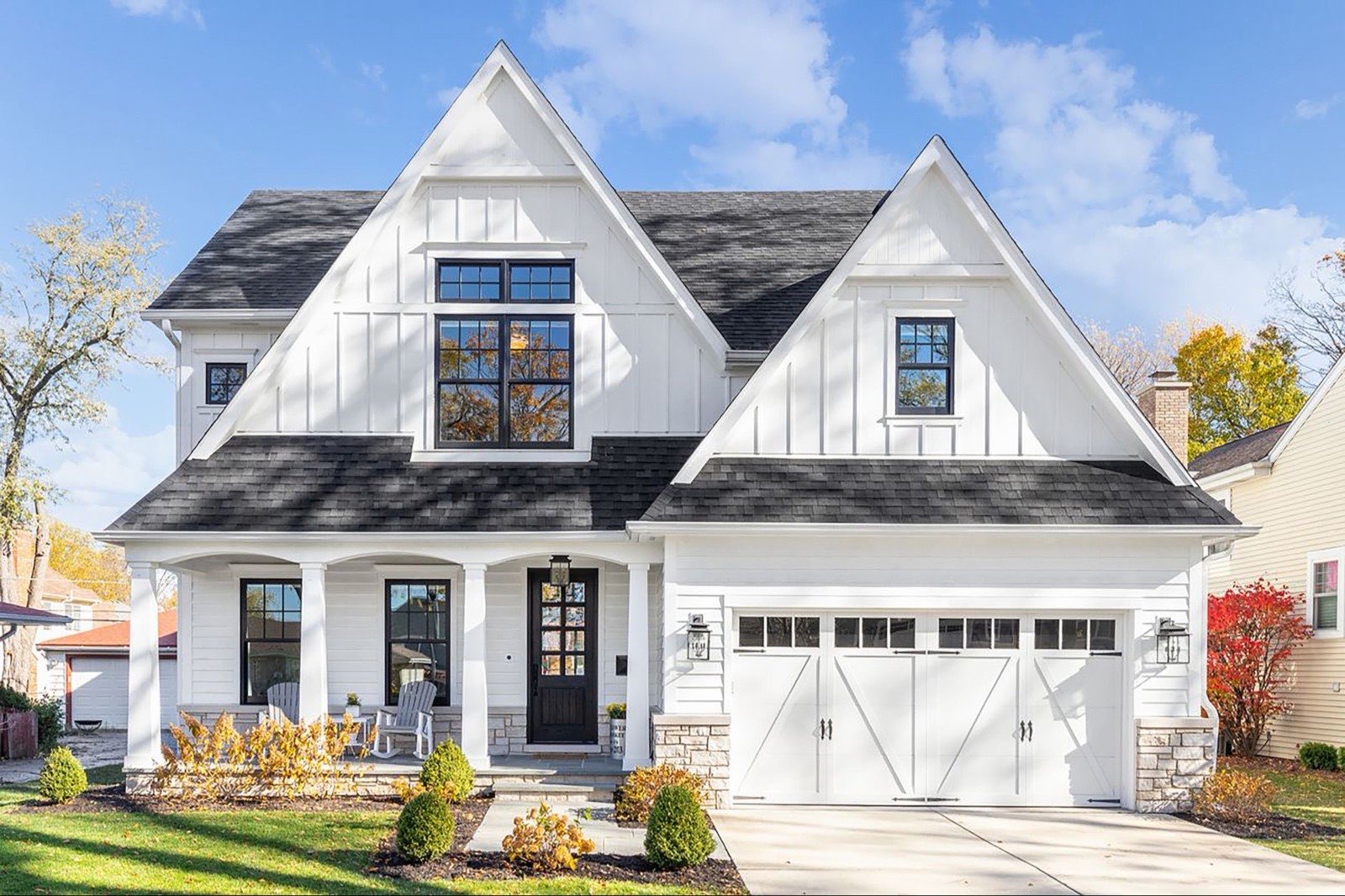 A white painted farmhouse exterior with white trim and a dark shingle roof.